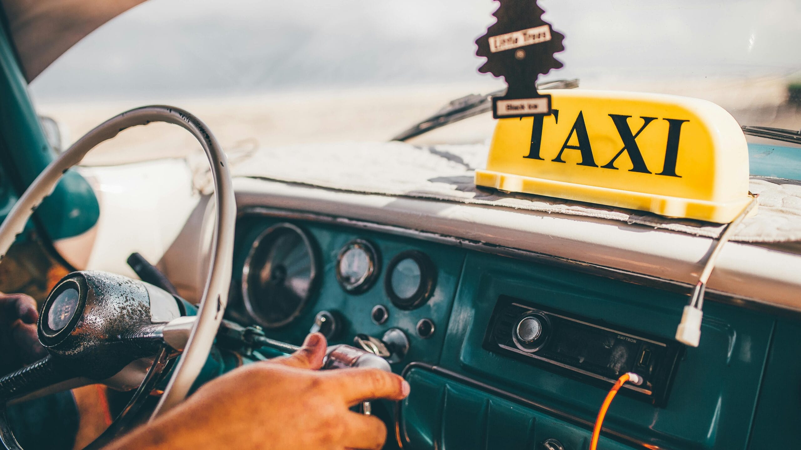 Interior view of a classic Cuban taxi with vintage steering wheel and taxi sign.